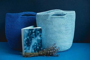 Two blue knitted handmade bag with flowers on a blue background. Copy, empty space for text photo