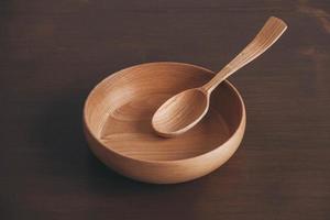 Empty wooden bowl and wooden spoon on a brown table background. Copy, empty space for text photo