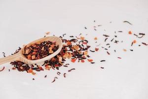 Dry fruit tea in a wooden spoon scattered on a white background. Top view. Copy, empty space for text photo