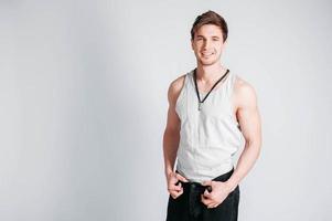 Portrait of a young muscular man in a light T-shirt and black jeans on a white background photo