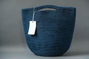 Blue handmade knitted bag on a gray background. Copy, empty space for text photo