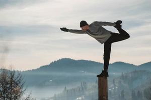 Man doing yoga exercises in front of amazing sunset on the winter mountains. Copy, empty space for text photo
