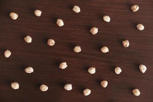 Dry chickpeas scattered on a brown wooden background. Top view. Copy, empty space for text photo