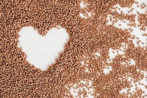 Buckwheat as a heart background texture on a white background photo