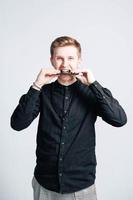 Young man in a black shirt with a smartphone in his hands on a white background. Copy, empty space for text photo