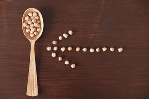 Raw chickpeas in a wooden spoon on a wooden background. Top view. Copy, empty space for text photo