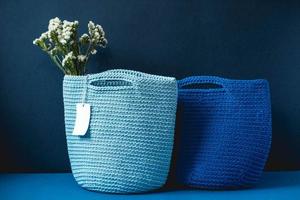 Two blue knitted handmade bag with flowers on a blue background. Copy, empty space for text photo