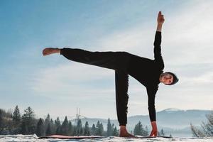 Man practicing yoga and balancing exercises in the winter mountains and enjoying life. Copy, empty space for text photo