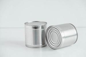 dos latas de metal cerradas de aluminio sobre una mesa blanca. copiar, espacio vacío para texto foto