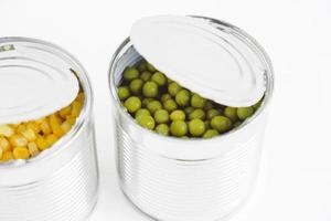 Two open cans with corn and peas on a white background. Copy, empty space for text photo