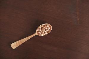 Raw chickpeas in a wooden spoon on a wooden background photo