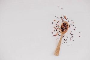 Dry fruit tea in a wooden spoon scattered on a white background. Top view. Copy, empty space for text photo