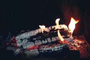 Firewood burning in the fireplace. Wood logs fire glowing in the dark. Copy, empty space for text