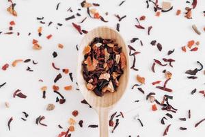 Dry fruit tea in a wooden spoon scattered on a white background. Top view. Copy, empty space for text photo