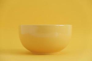 Yellow empty ceramic bowl on a yellow background. Copy, empty space for text photo