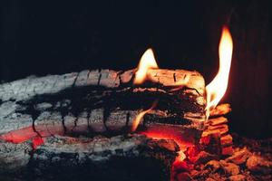 Firewood burning in the fireplace. Wood logs fire glowing in the dark. Closeup view photo