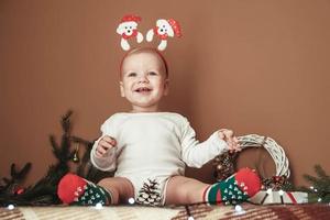 Beautiful little baby boy celebrating Christmas. Funny child wearing in a Christmas suit near Christmas tree in room photo