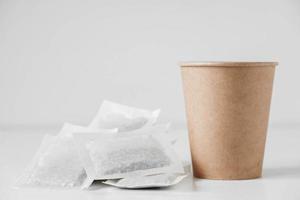 Paper cup and bags with tea on a white background. Copy, empty space for text photo