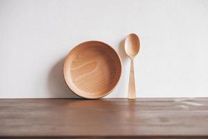 Empty wooden bowl and wooden spoon on a brown table background. Copy, empty space for text photo