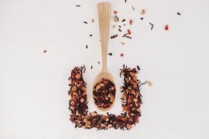 Dry fruit tea in a wooden spoon scattered on a white background. Top view. Copy, empty space for text photo