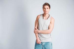 Young muscular man in a light T-shirt and jeans on a white background photo