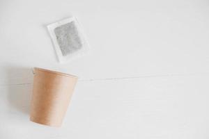 Paper cup and square dry tea bag on a white background. Top view. Copy, empty space for text photo