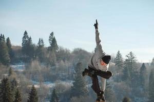 un anciano caucásico haciendo ejercicios de yoga frente a una increíble puesta de sol en las montañas de invierno. copiar, espacio vacío para texto foto