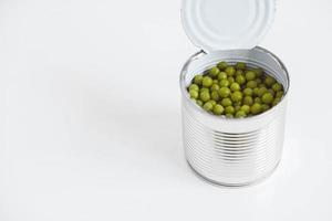 Canned green sweet peas in an open aluminum metal can on a white table. Copy, empty space for text photo