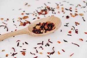 Dry fruit tea in a wooden spoon scattered on a white background. Top view. Copy, empty space for text photo