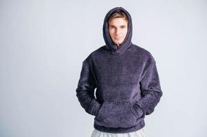 Portrait of a young man in purple sweatshirt with hood on a white background. Copy, empty space for text photo