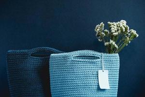 Two blue knitted handmade bag with flowers on a blue background. Copy, empty space for text photo