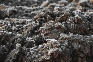 Frozen ground with hoarfrost on a farm field. Focus on frozen soil. Copy, empty space for text. Weather forecast and development time strategy for sowing growing crops photo