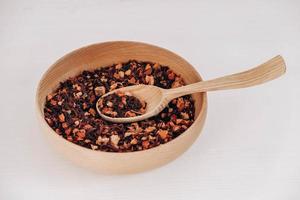 Dry fruit tea in a wooden spoon and a wooden plate on a white background. Top view. Copy, empty space for text photo