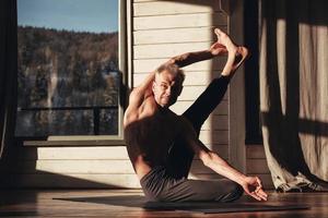 Man with a naked torso practicing yoga training in studio in front of a window. Copy, empty space for text photo