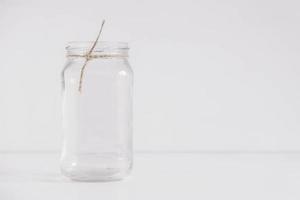 Glass transparent jar on a white table and wall background. Copy, empty space for text photo