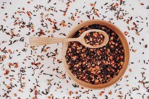 Dry fruit tea in a wooden spoon and a wooden plate on a white background. Top view. Copy, empty space for text photo