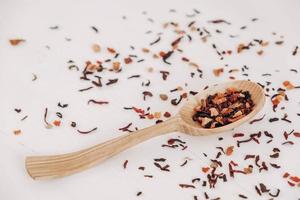 Dry fruit tea in a wooden spoon scattered on a white background. Top view. Copy, empty space for text photo