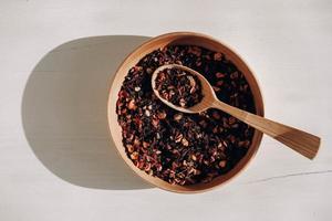 Dry fruit tea in a wooden spoon and a wooden plate on a white background. Top view. Copy, empty space for text photo