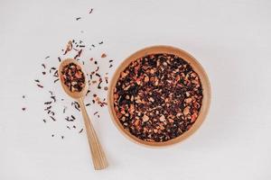 Dry fruit tea in a wooden spoon scattered on a white background. Top view. Copy, empty space for text photo