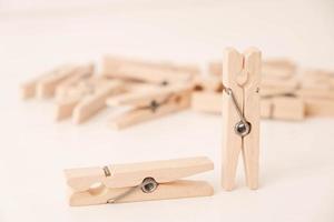 Many wooden clothespins on a white table background photo