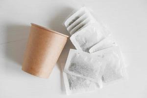 Paper cup and bags with tea on a white background. Top view. Copy, empty space for text photo