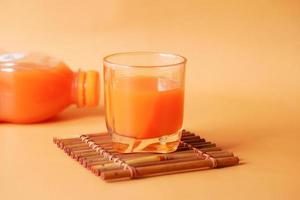 glass of orange juice and bottle on color color background photo