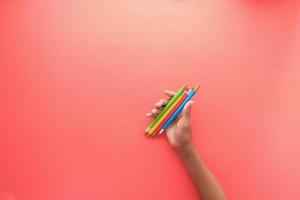 child girl holding many color pencils on red background photo