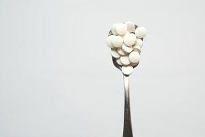 high angle view of pills on spoon on white , top view photo