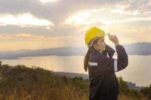 a woman engineer is putting a protective helmet on her head at sunset. photo