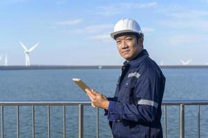 a man engineer is wearing a protective helmet on her head, using tablet Analytics engineering data. photo