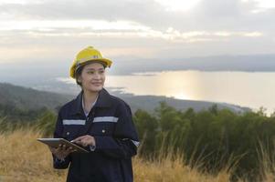 una ingeniera lleva un casco protector en la cabeza y utiliza datos de ingeniería de análisis de tabletas. foto