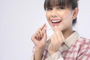 joven mujer sonriente sosteniendo llaves invisalign sobre estudio de fondo blanco, cuidado de la salud dental y concepto de ortodoncia. foto