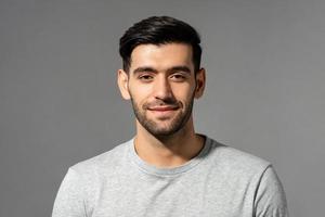 primer plano retrato de un joven y apuesto hombre caucásico sonriente mirando a la cámara en un estudio aislado de fondo gris claro foto