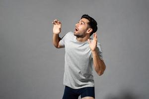 Surprised shocked young Caucasian man with open hands gesture looking aside and gsaping in light gray isolated studio background photo